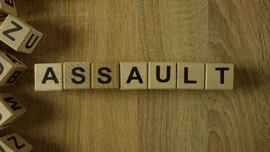 6 Legal Defenses That Can Help Beat Assault Charges’ with legal icons such as a gavel, shield, and law book.